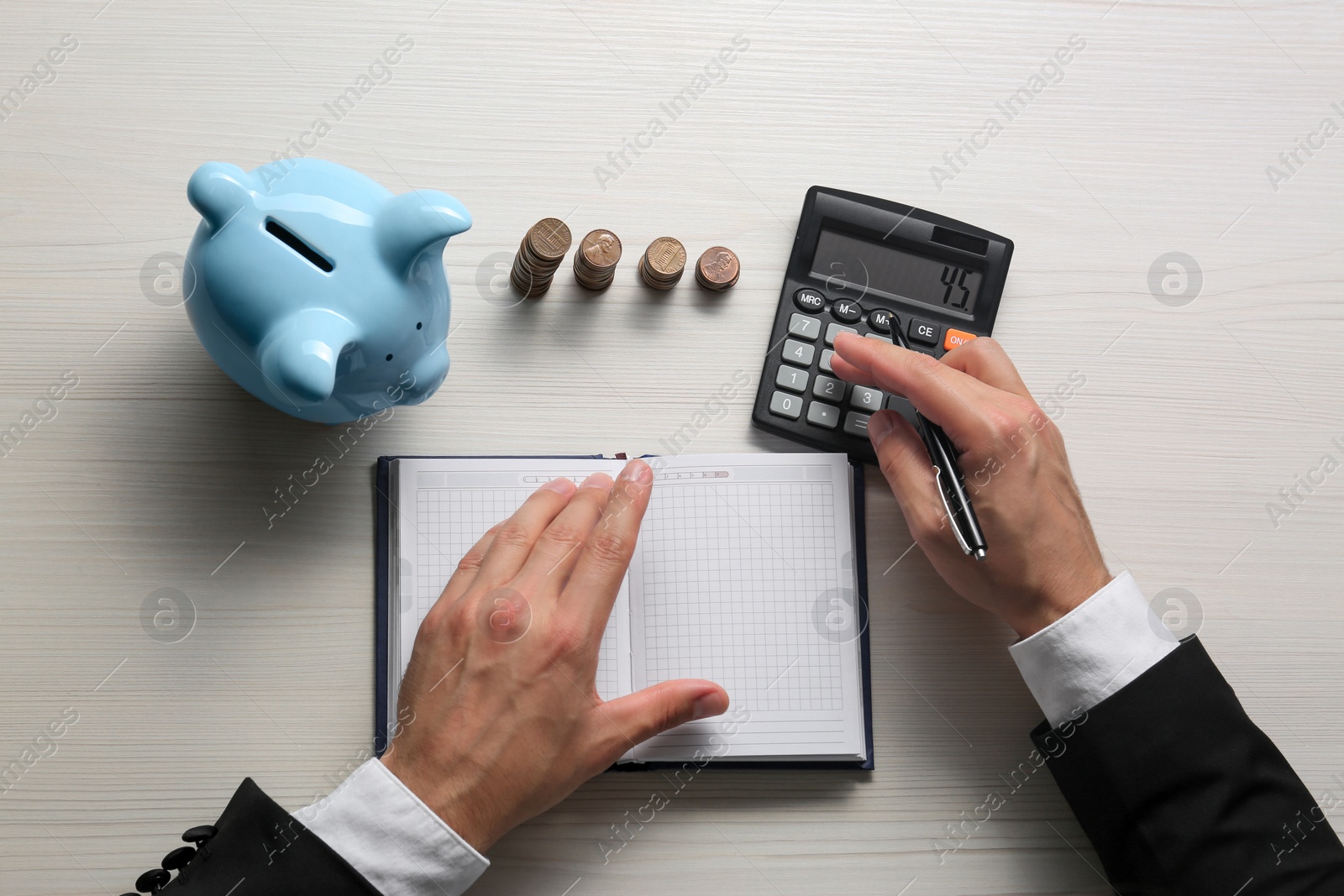 Photo of Businessman calculating at light wooden table, top view