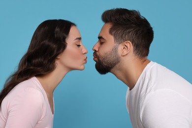 Photo of Cute young couple kissing on light blue background