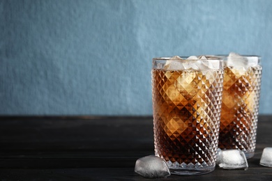 Glasses of refreshing cola with ice cubes on table. Space for text