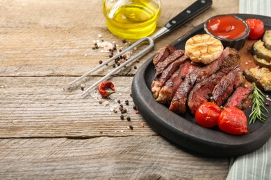 Photo of Delicious grilled beef with vegetables and spices on wooden table, space for text