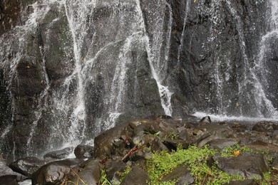Photo of Picturesque view of small waterfall near rock outdoors