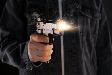 Image of Man shooting handgun on black background, closeup