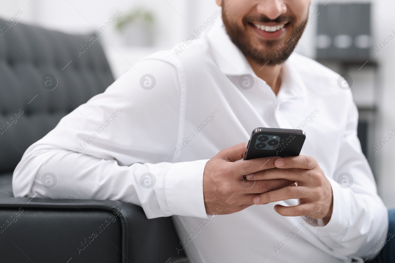 Photo of Young man using smartphone indoors, selective focus