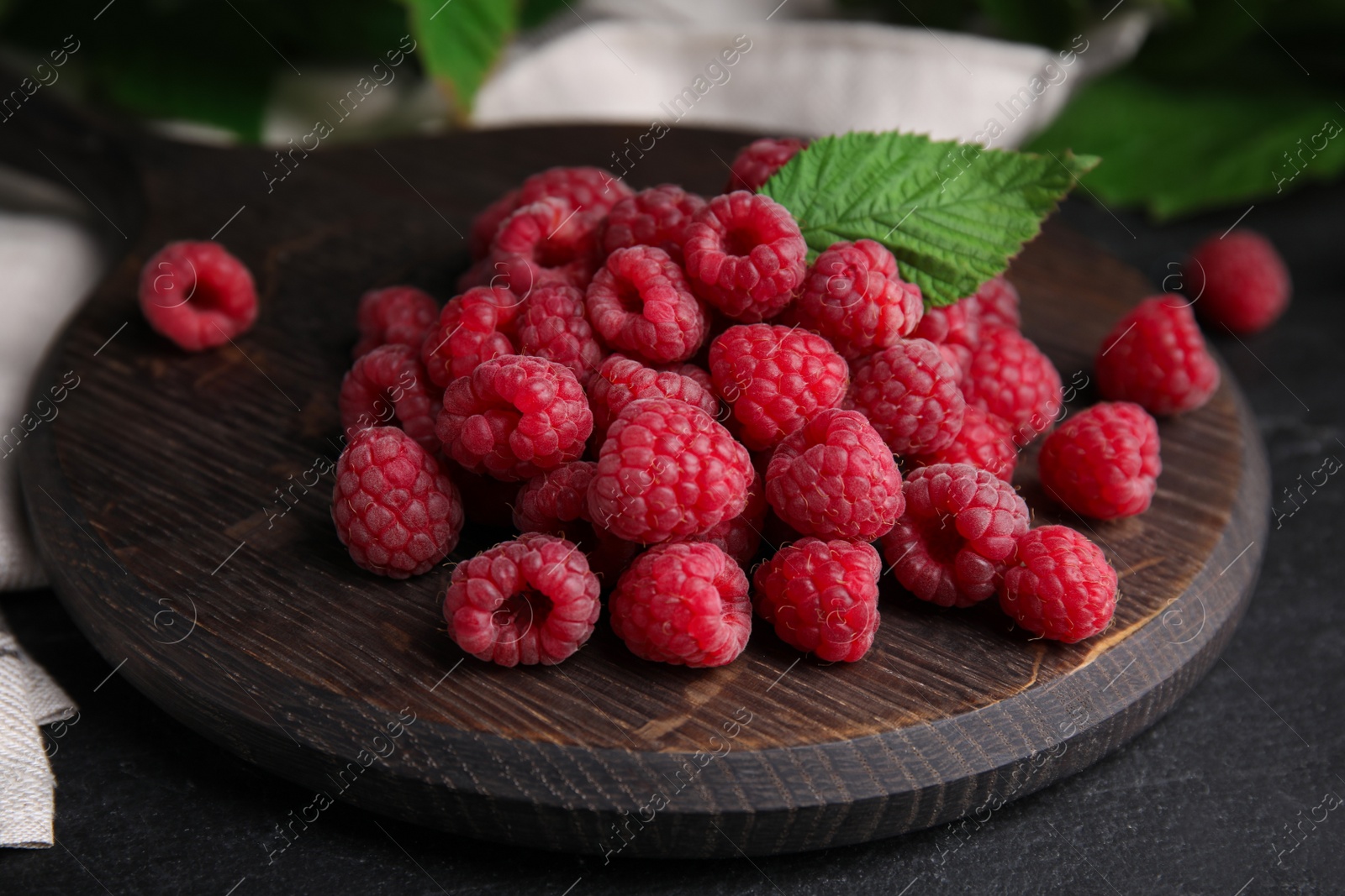 Photo of Wooden board with fresh ripe raspberries on table, closeup