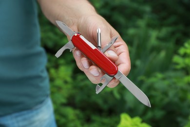 Man holding compact portable multitool outdoors, closeup