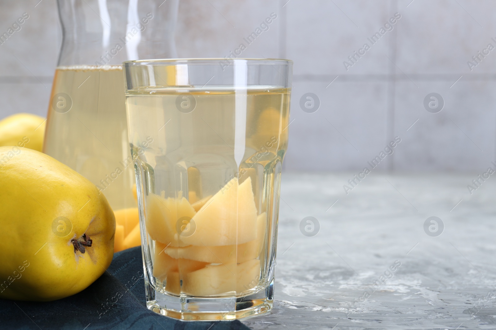 Photo of Delicious quince drink and fresh fruits on grey table, closeup. Space for text