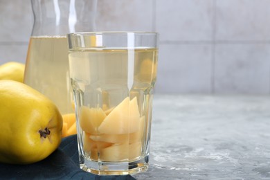 Photo of Delicious quince drink and fresh fruits on grey table, closeup. Space for text