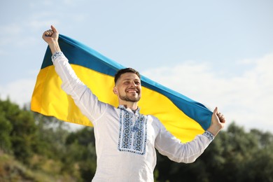 Photo of Man in vyshyvanka with flag of Ukraine outdoors