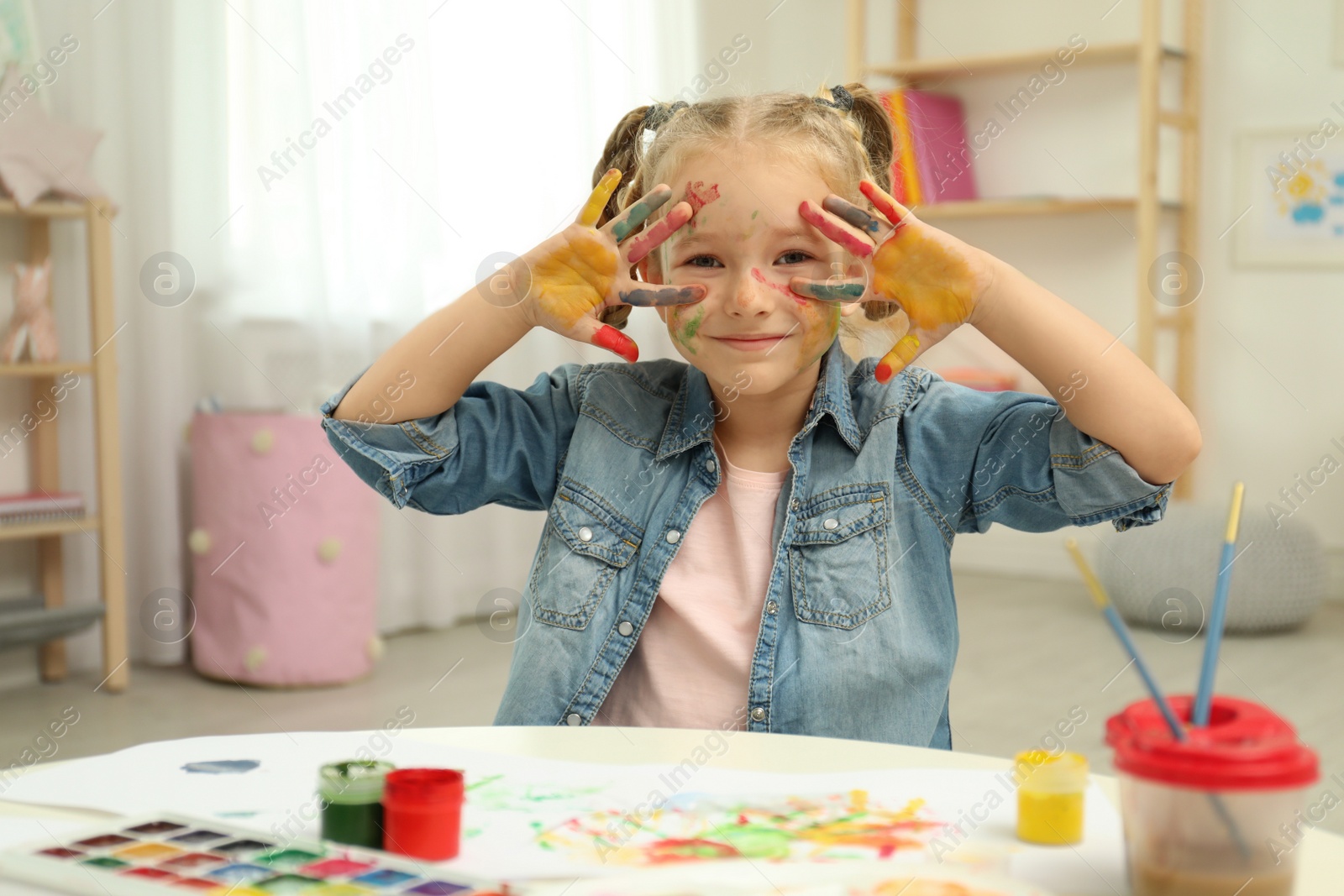 Photo of Cute little child painting with palms at table