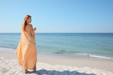 Woman with beach towel near sea on sunny day