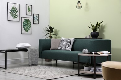 Photo of Stylish living room interior with comfortable green sofa and floral pictures