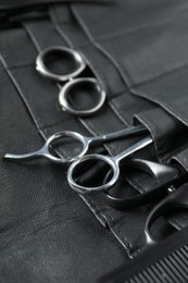 Hairdresser tools. Professional scissors and comb in leather organizer, closeup