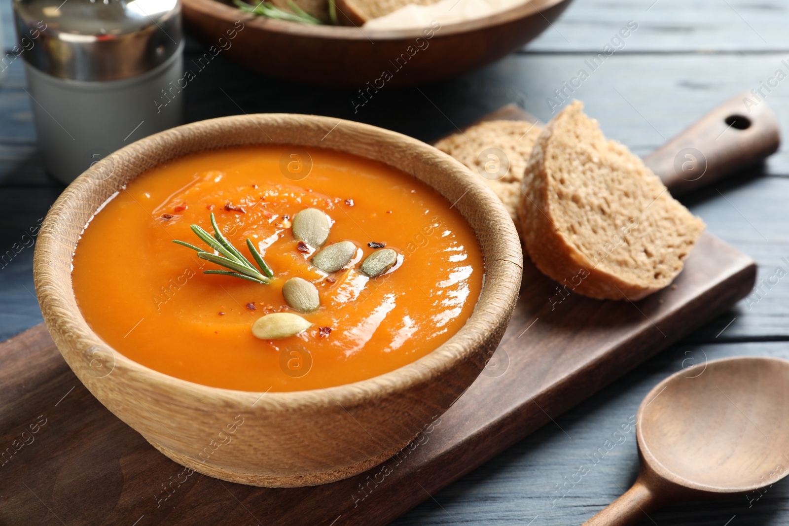 Photo of Board with bowl of sweet potato soup served on table. Space for text