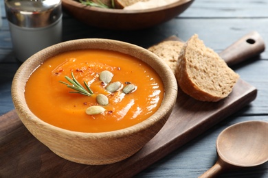 Board with bowl of sweet potato soup served on table. Space for text