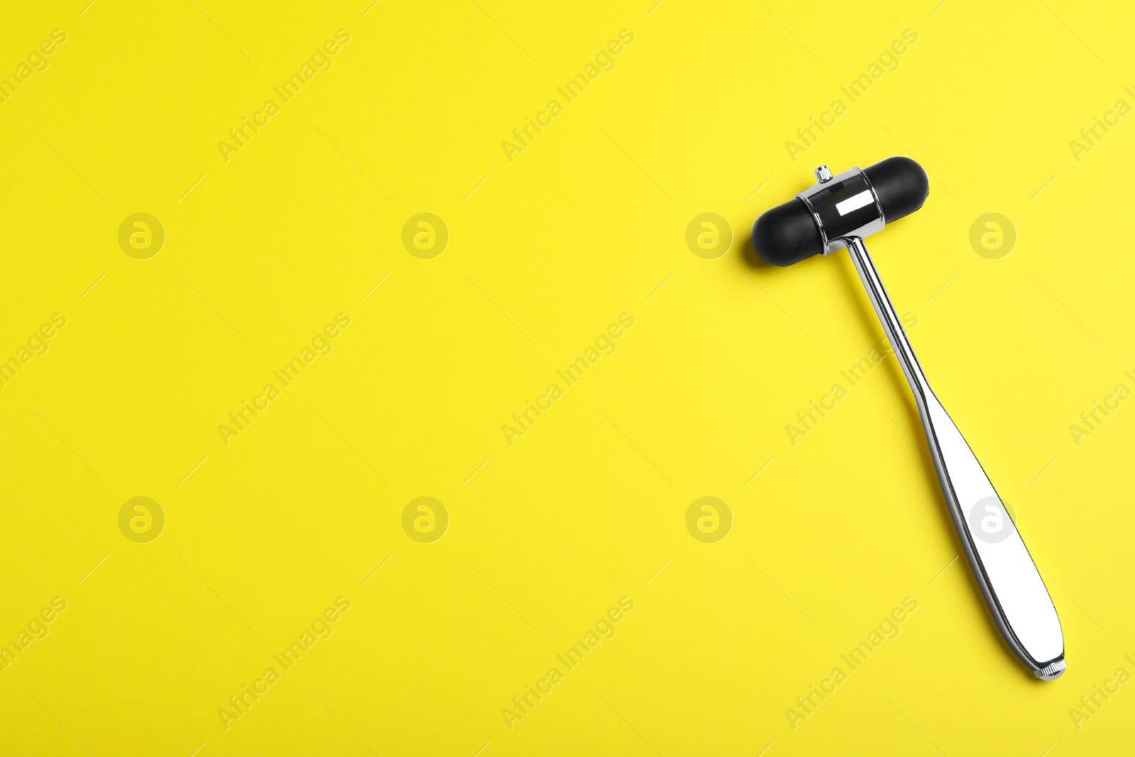 Photo of Reflex hammer on yellow background, top view with space for text. Nervous system diagnostic