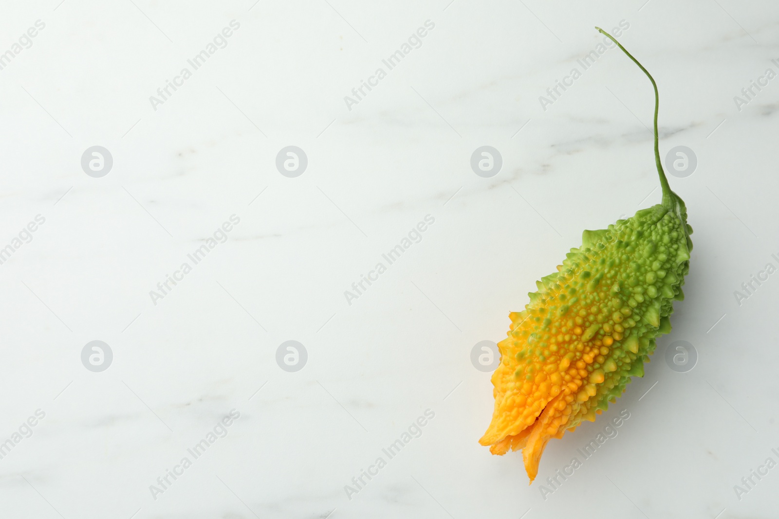 Photo of Bitter melon on white marble table, top view. Space for text