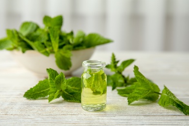 Bottle of essential oil and mint on table