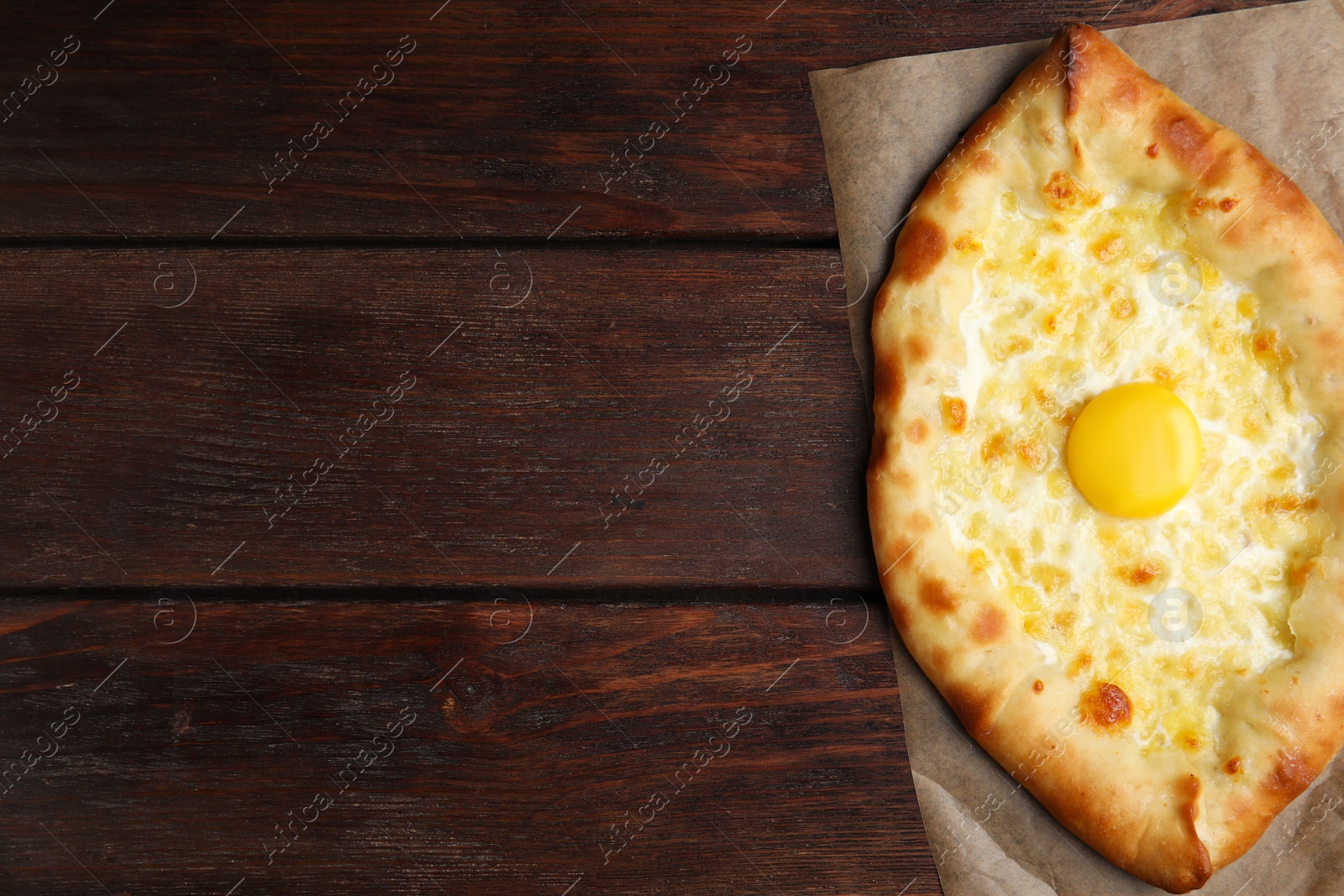 Photo of Fresh homemade khachapuri with cheese and egg on wooden table, top view. Space for text