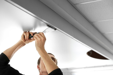 Photo of Repairman installing white stretch ceiling in room, closeup