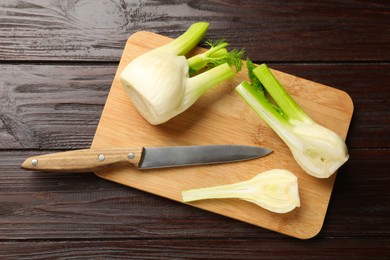 Photo of Fresh raw fennel bulbs and knife on wooden table, top view