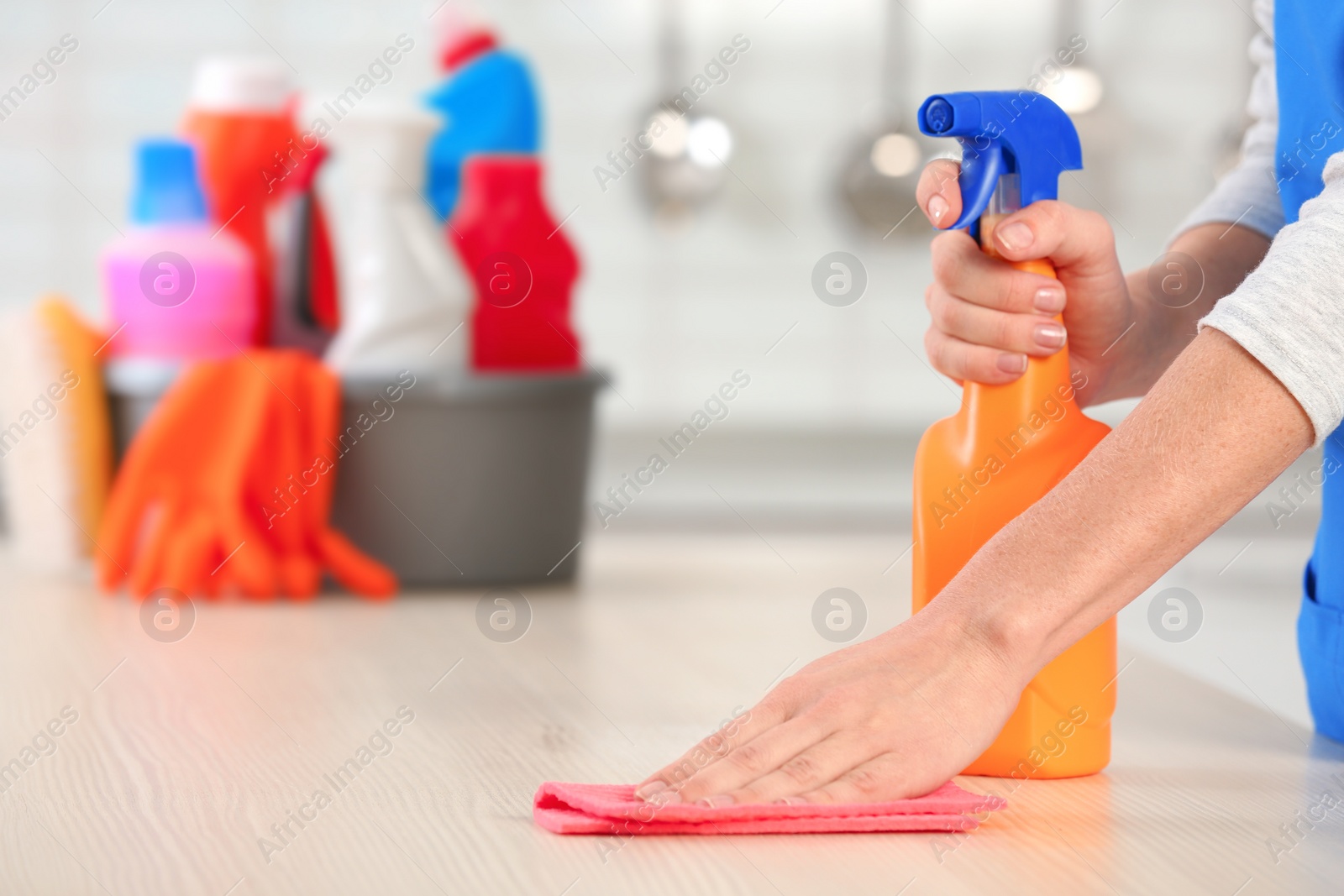 Photo of Woman cleaning table with rag in kitchen, closeup. Space for text