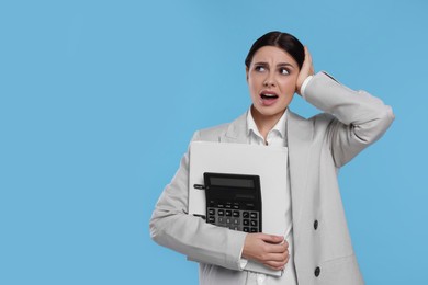 Photo of Emotional accountant with calculator and folder on light blue background, space for text