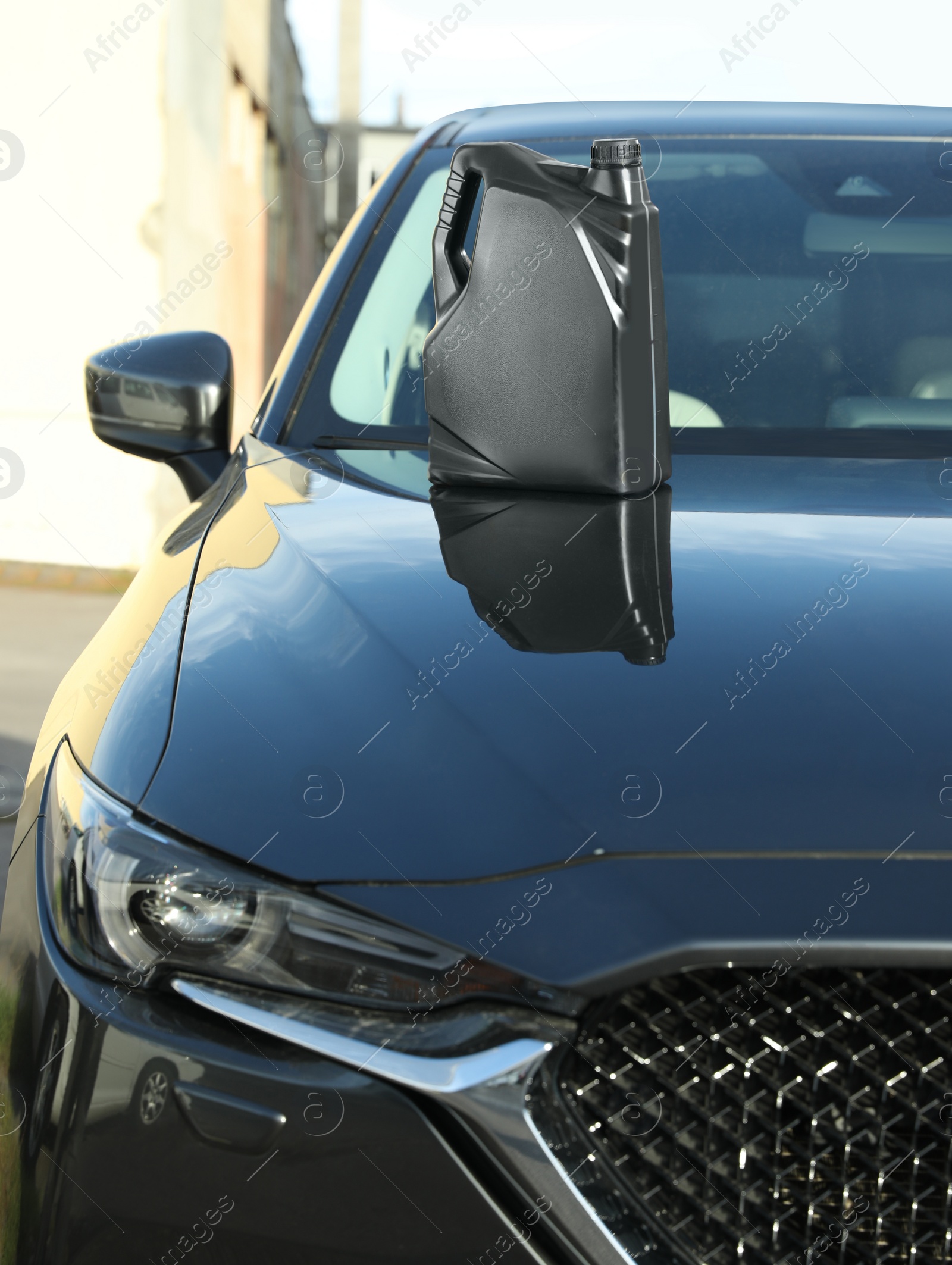 Photo of Black canister with motor oil on hood of car outdoors