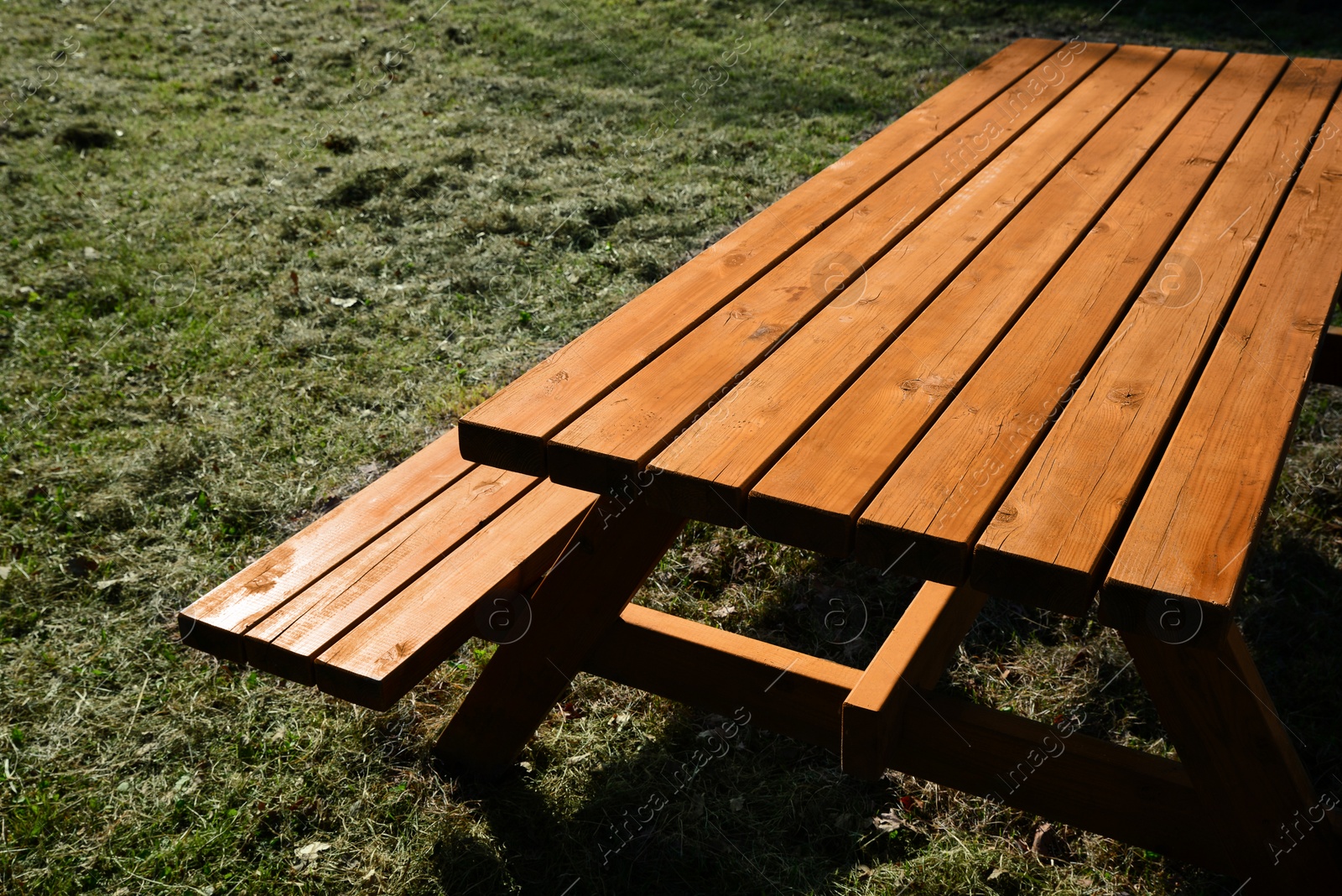 Photo of Empty wooden picnic table with bench outdoors on sunny day