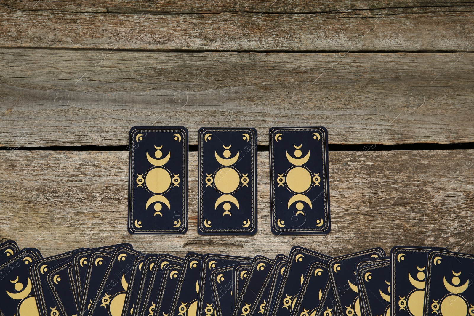 Photo of Tarot cards on wooden table, top view and space for text. Reverse side