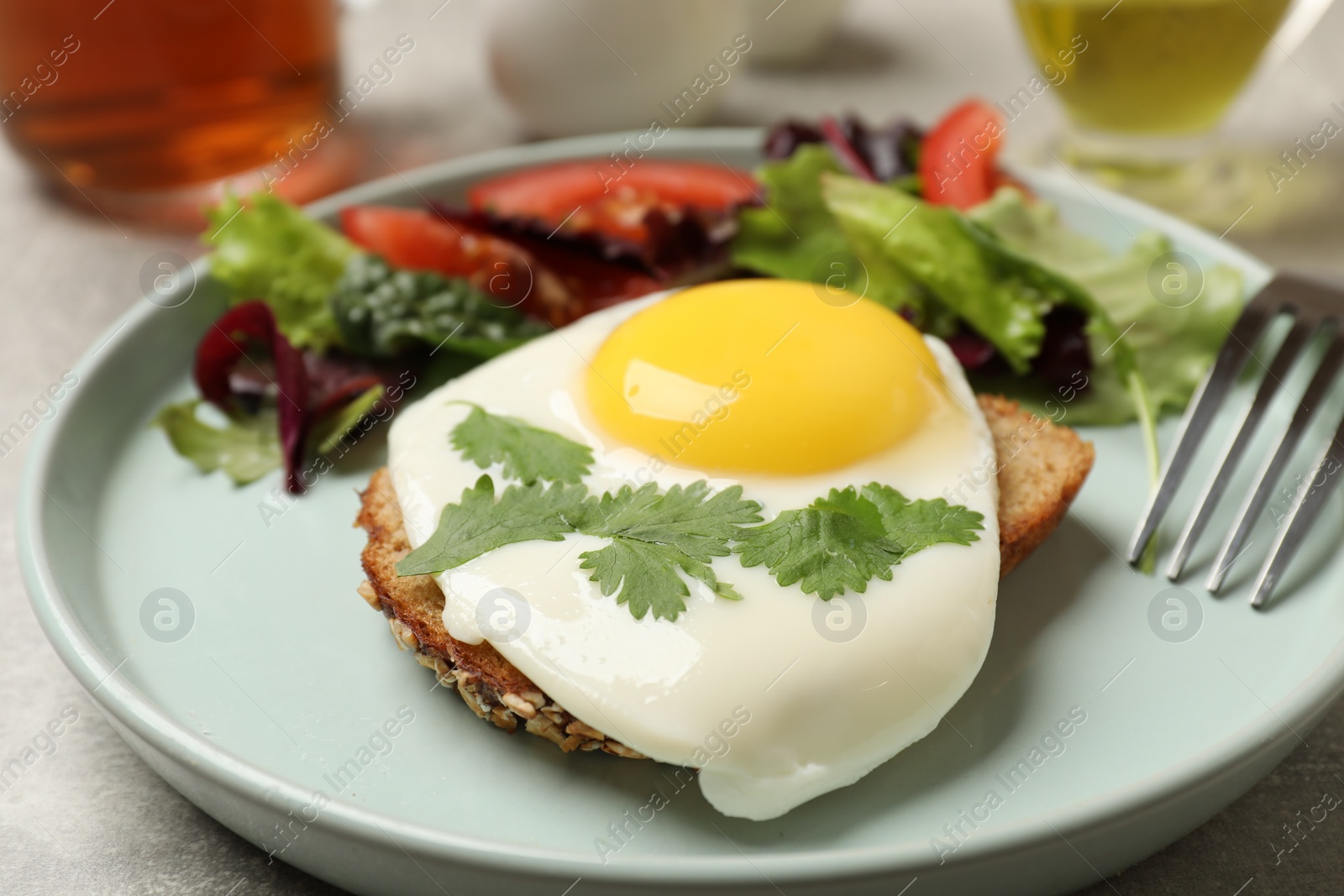 Photo of Delicious breakfast with fried egg and salad served on light grey table, closeup