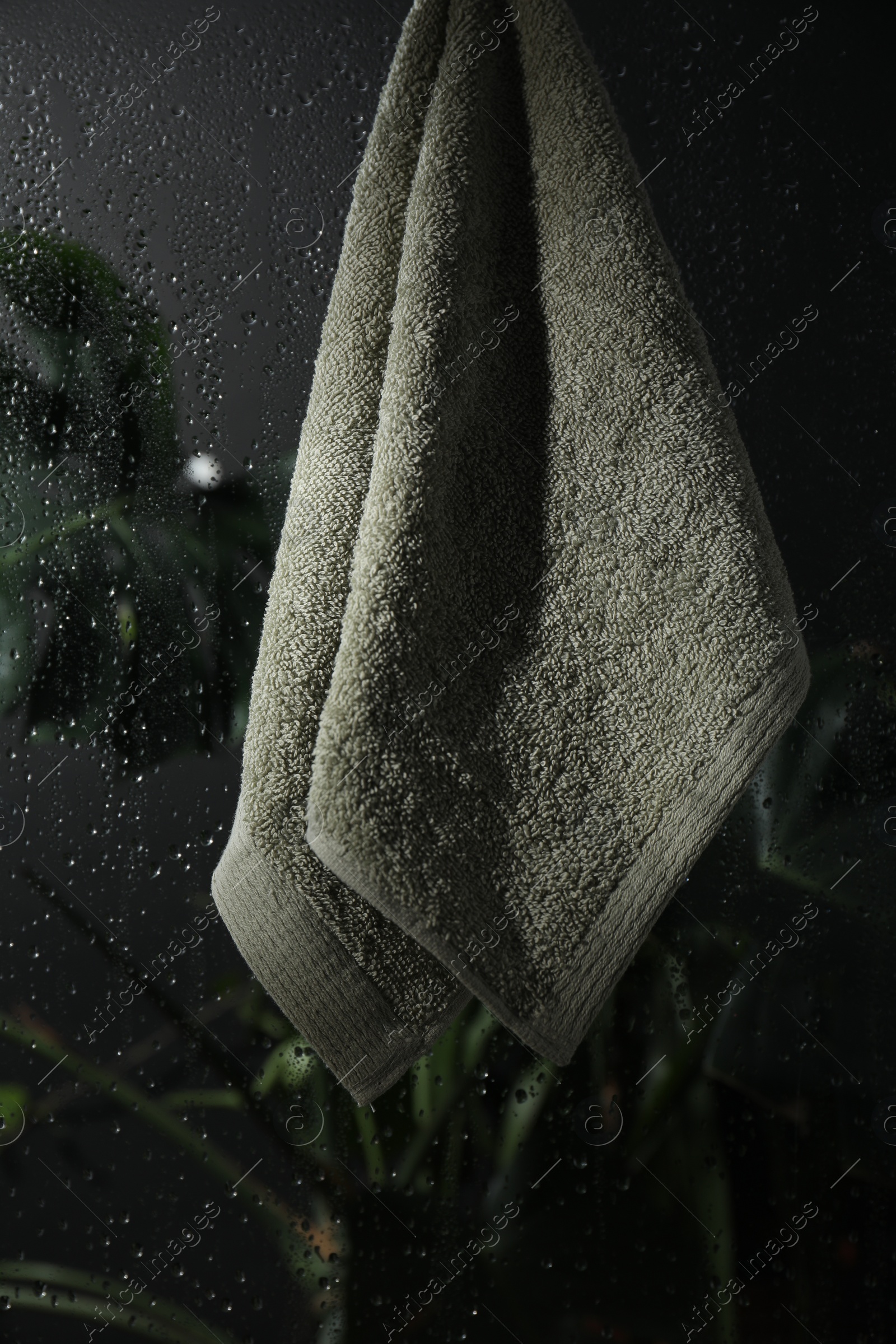 Photo of Terry towel hanging on wet glass wall in shower