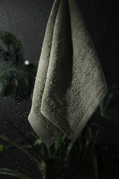 Terry towel hanging on wet glass wall in shower