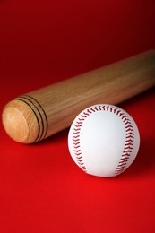 Photo of Wooden baseball bat and ball on red background. Sports equipment