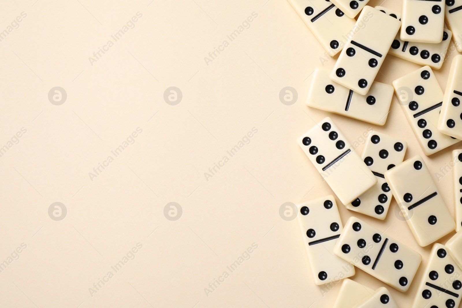 Photo of Classic domino tiles on beige background, flat lay. Space for text