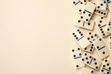 Photo of Classic domino tiles on beige background, flat lay. Space for text