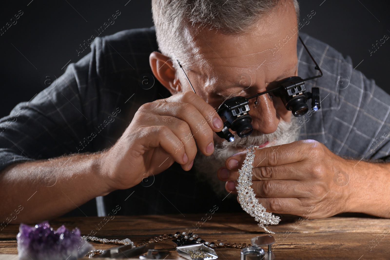 Photo of Male jeweler evaluating diamond necklace in workshop