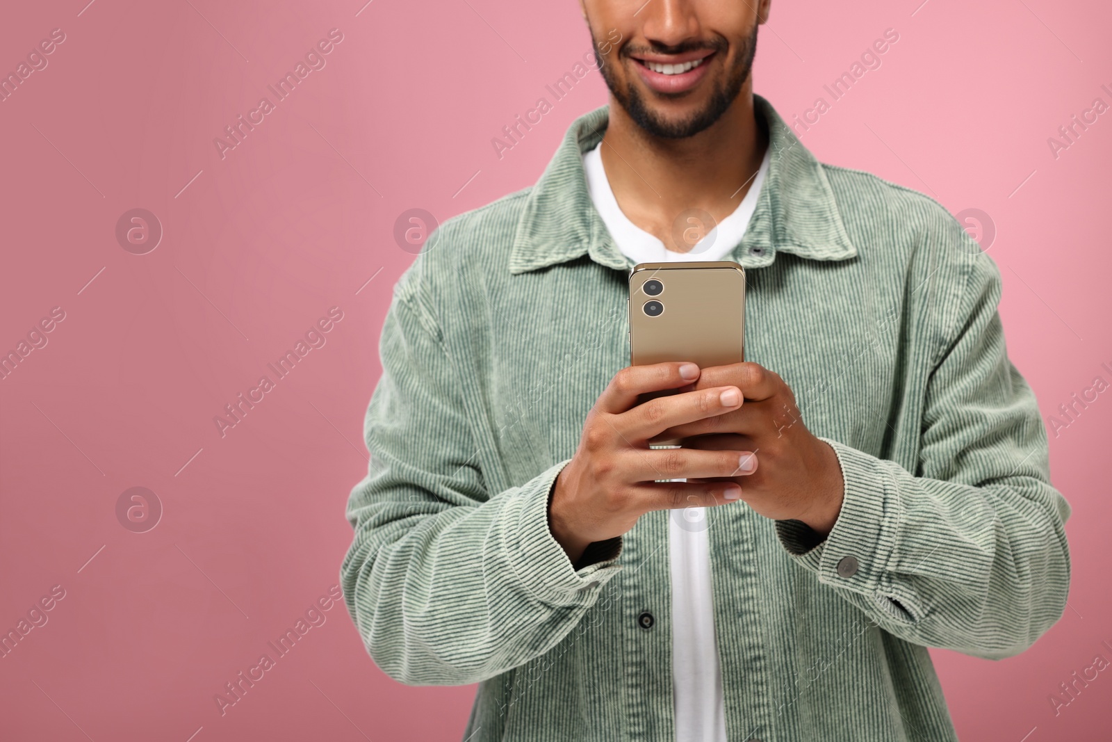 Photo of Man sending message via smartphone on pink background, closeup. Space for text