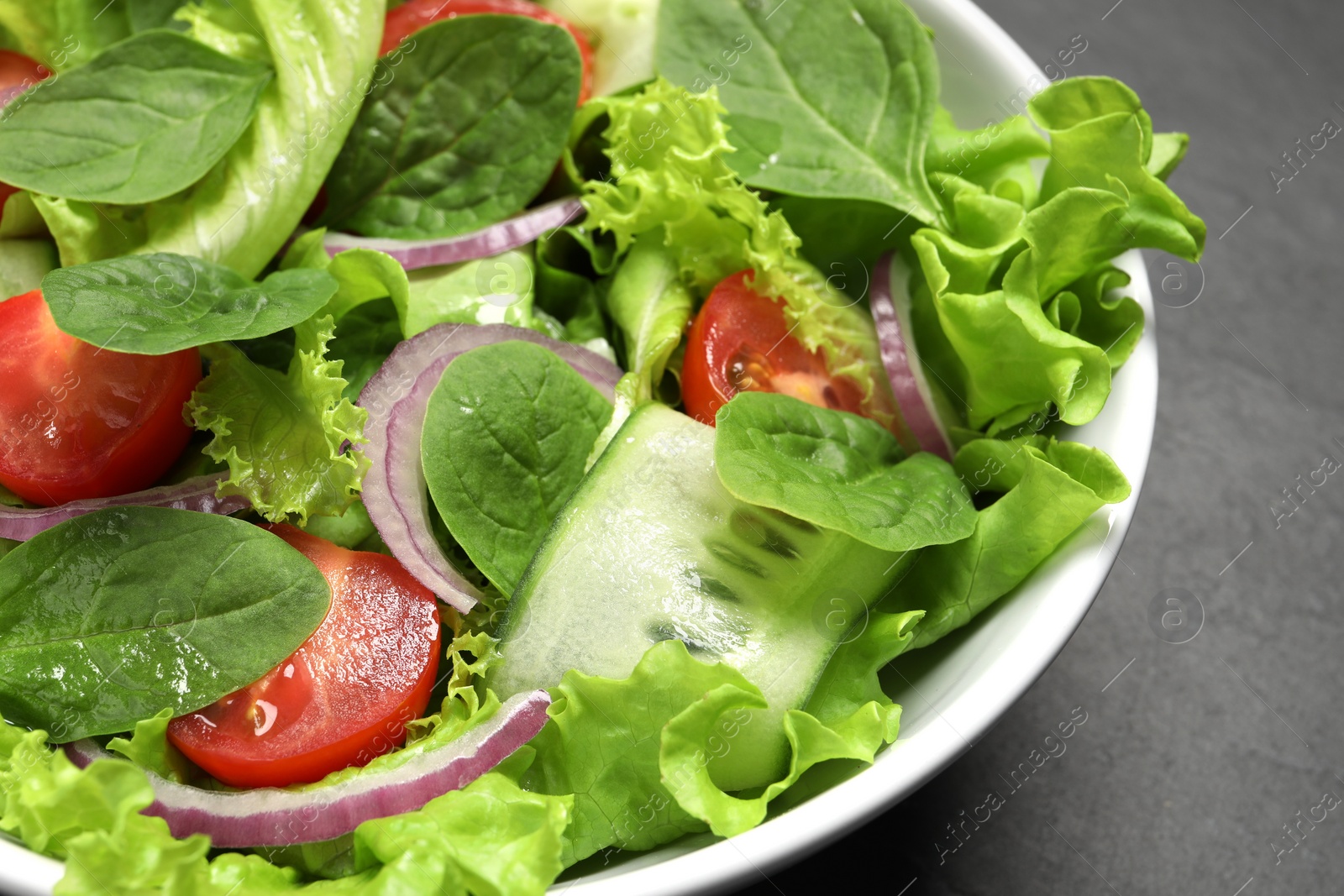 Photo of Delicious vegetable salad on grey table, closeup