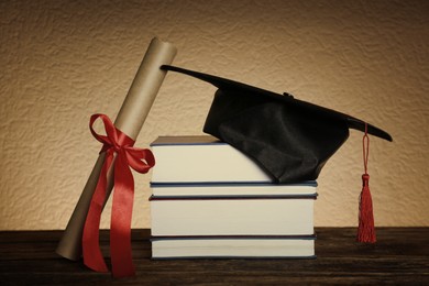 Image of Graduation hat, books and diploma on wooden table
