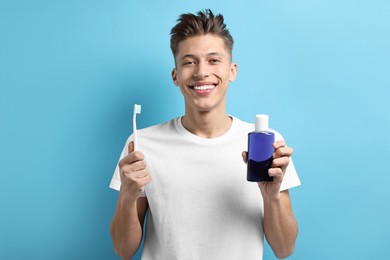 Photo of Young man with mouthwash and toothbrush on light blue background