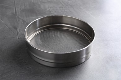 Photo of One metal sieve on grey table. Cooking utensil