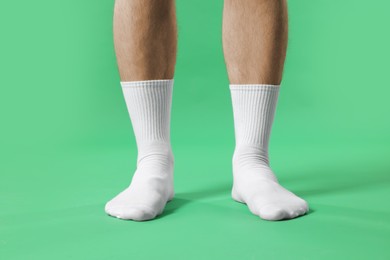 Photo of Man in stylish white socks on green background, closeup