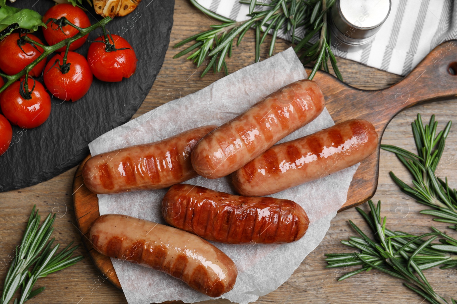 Photo of Tasty grilled sausages served on wooden table, flat lay