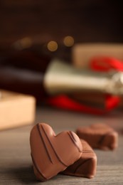 Photo of Tasty heart shaped chocolate candies on wooden table, closeup. Happy Valentine's day