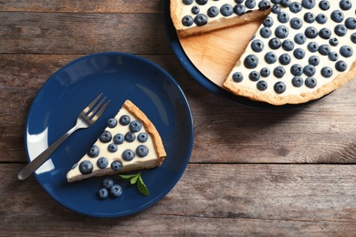 Flat lay composition with piece of tasty blueberry cake on wooden table