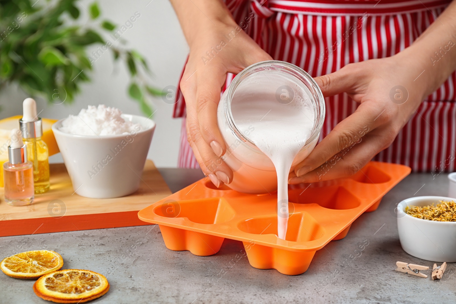 Photo of Woman making natural handmade soap at grey stone table, closeup