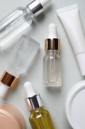 Photo of Many bottles and tube of cosmetic serum on light grey background, flat lay