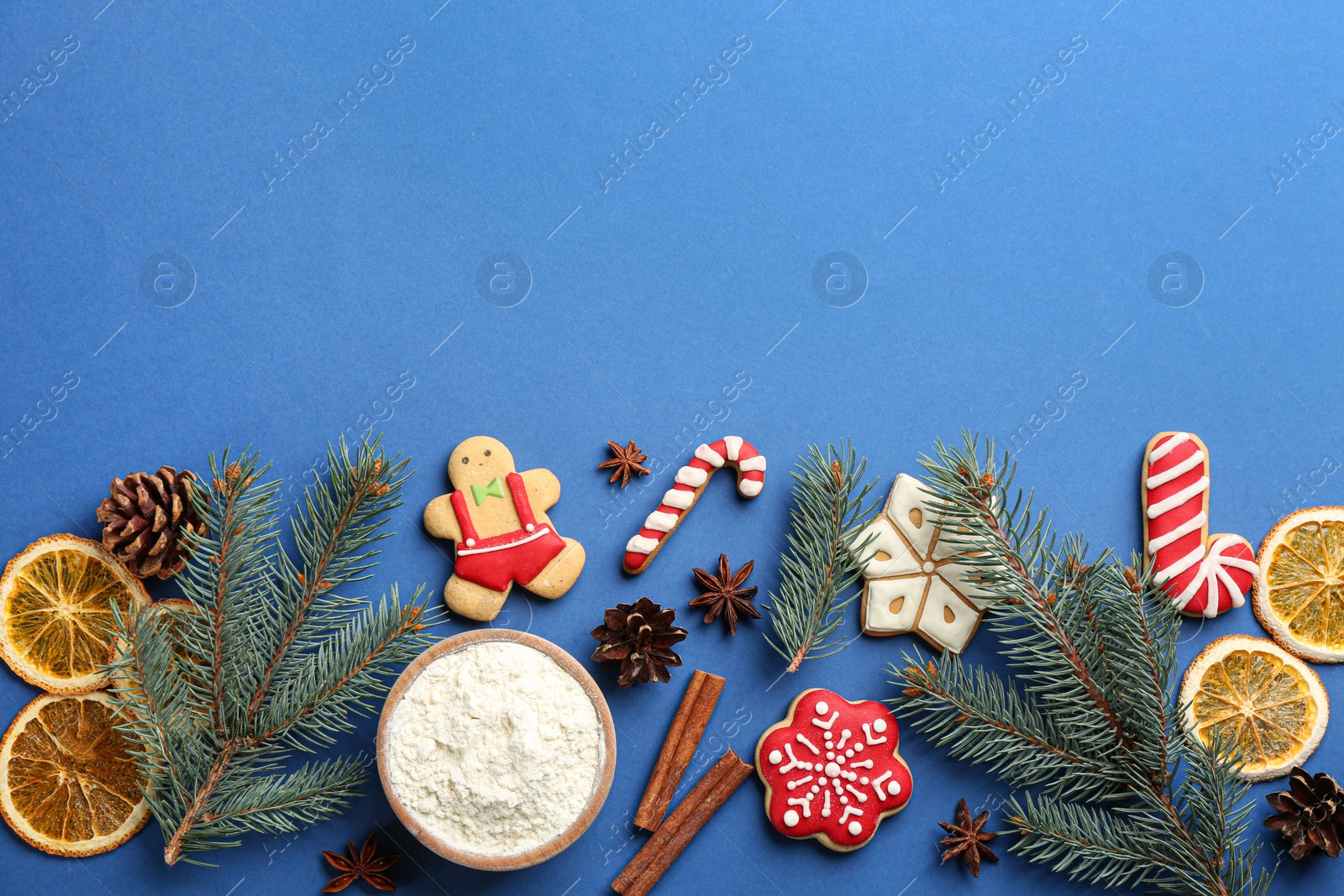 Photo of Flat lay composition with Christmas cookies and flour on blue background. Space for text