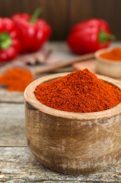 Photo of Bowl with aromatic paprika powder on old wooden table