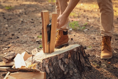 Man chopping firewood with axe in forest, closeup